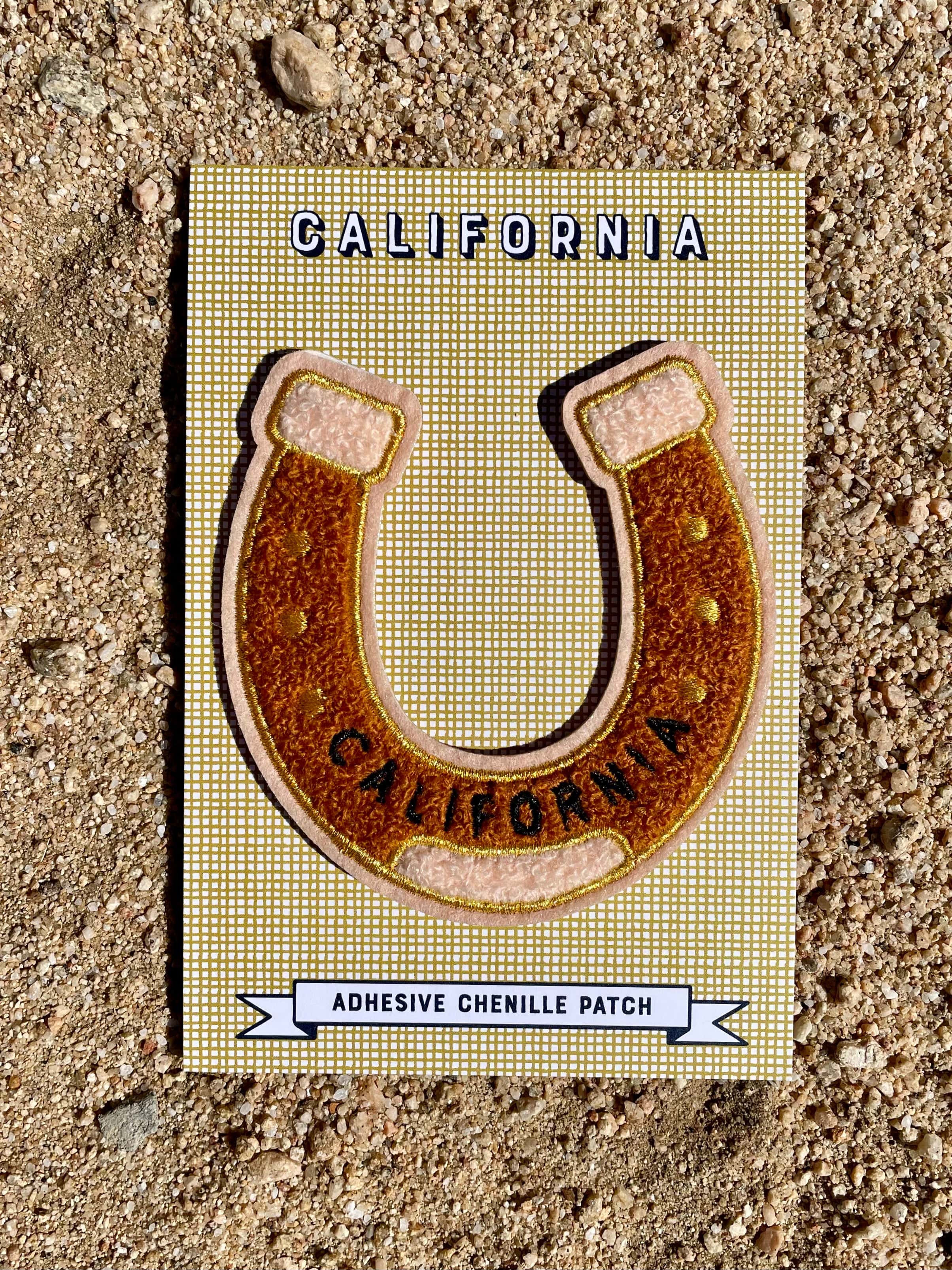 An adhesive chenille patch designed as a horseshoe with 'California' text, placed on a card with the same design.