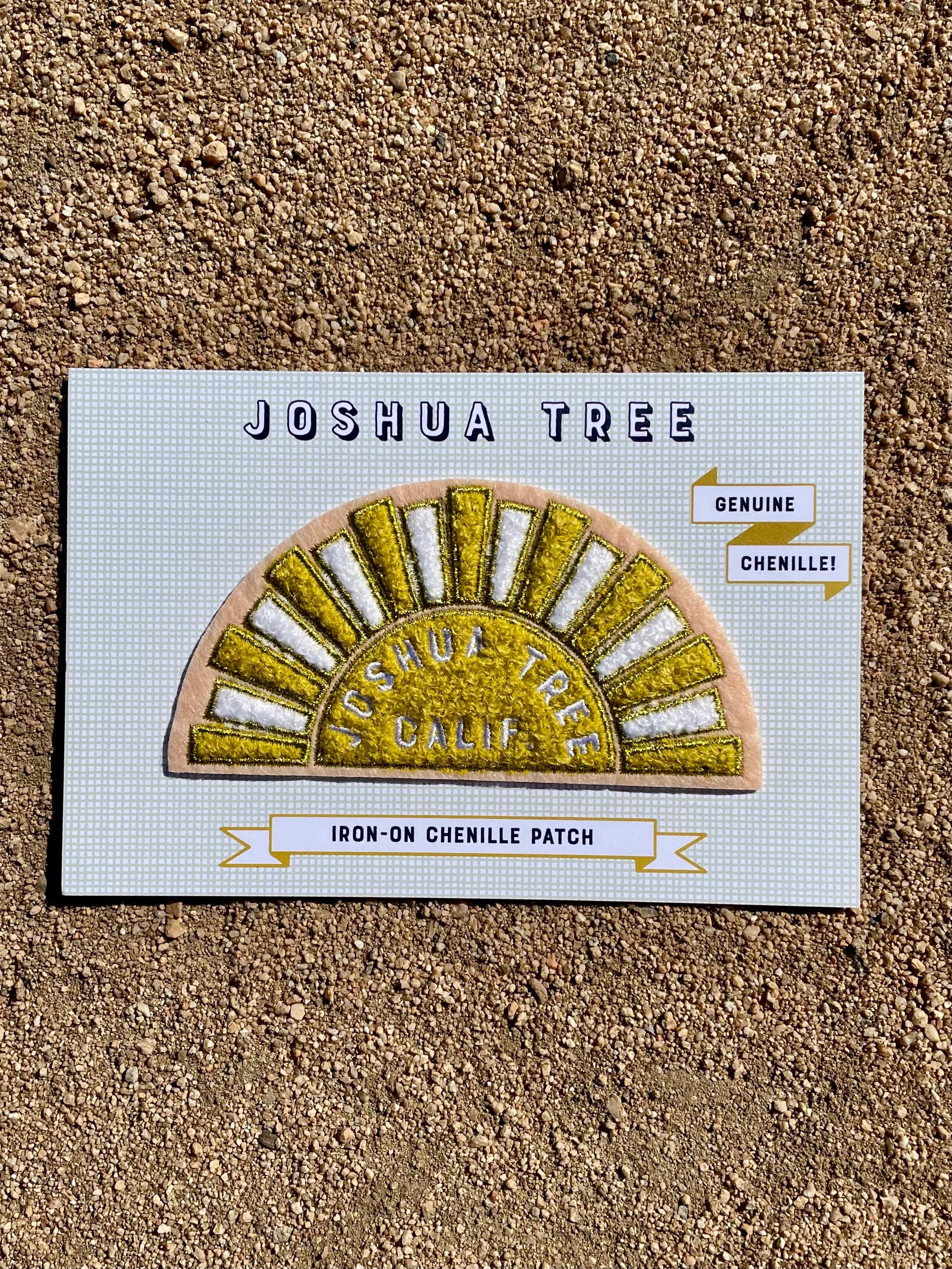 A chenille patch depicting a stylized yellow and white sun with 'Joshua Tree Calif.' text, designed on a pink felt base with gold metallic embroidered details.
