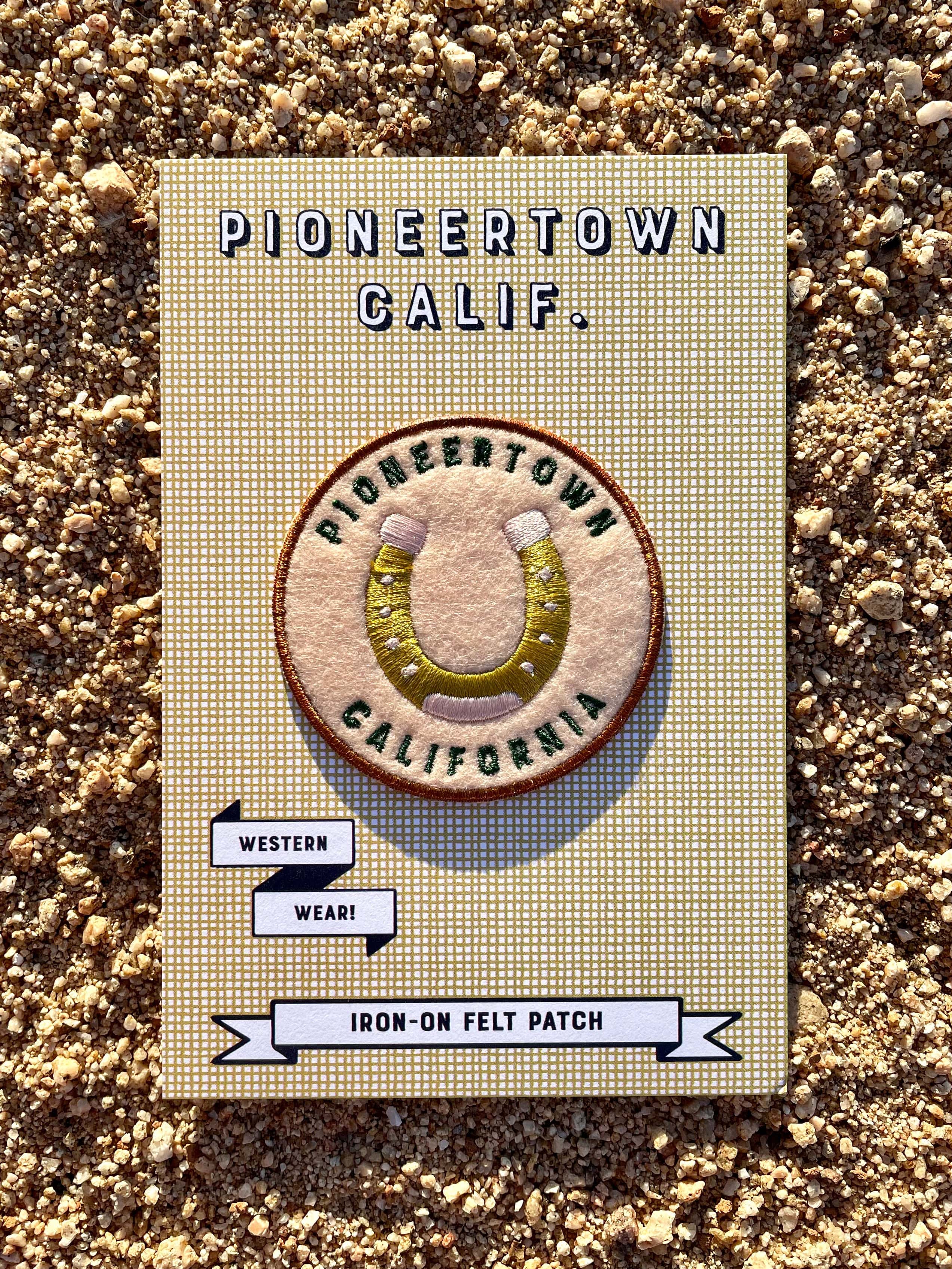 A round felted patch picturing a horseshoe and the text 'Pioneertown California'.