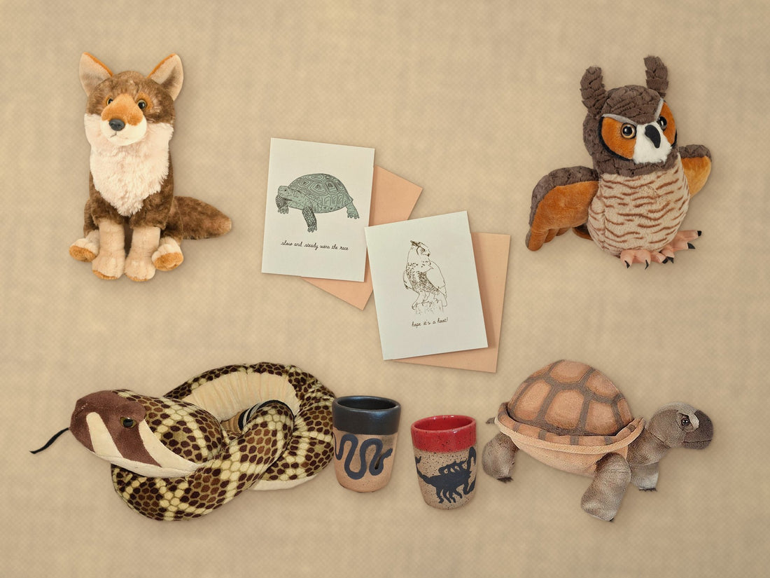 Desert critter plushies, Stray Ceramics snake and scorpion shot cups, and Opal Atlas cards laid out on sand linen