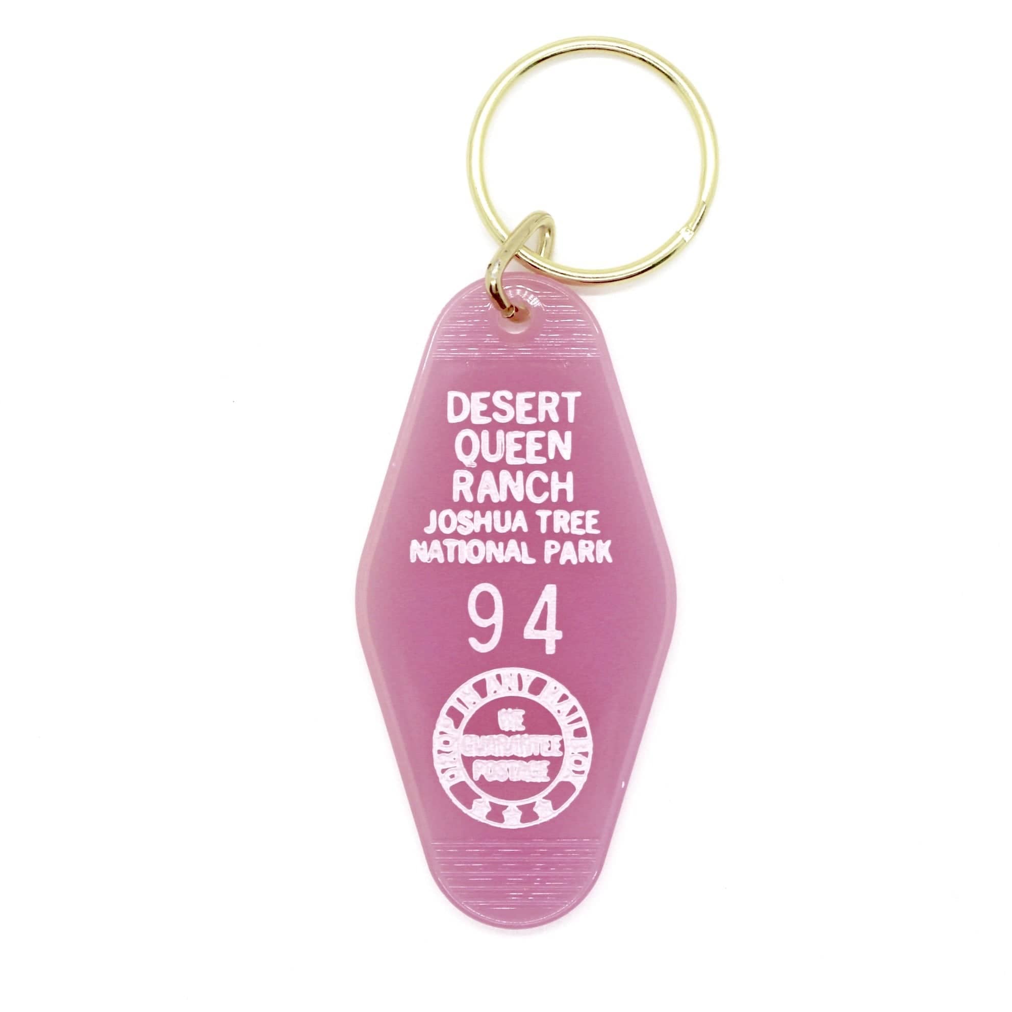 Pink motel keychain with gold key ring that reads DESERT QUEEN RANCH JOSHUA TREE NATIONAL PARK 