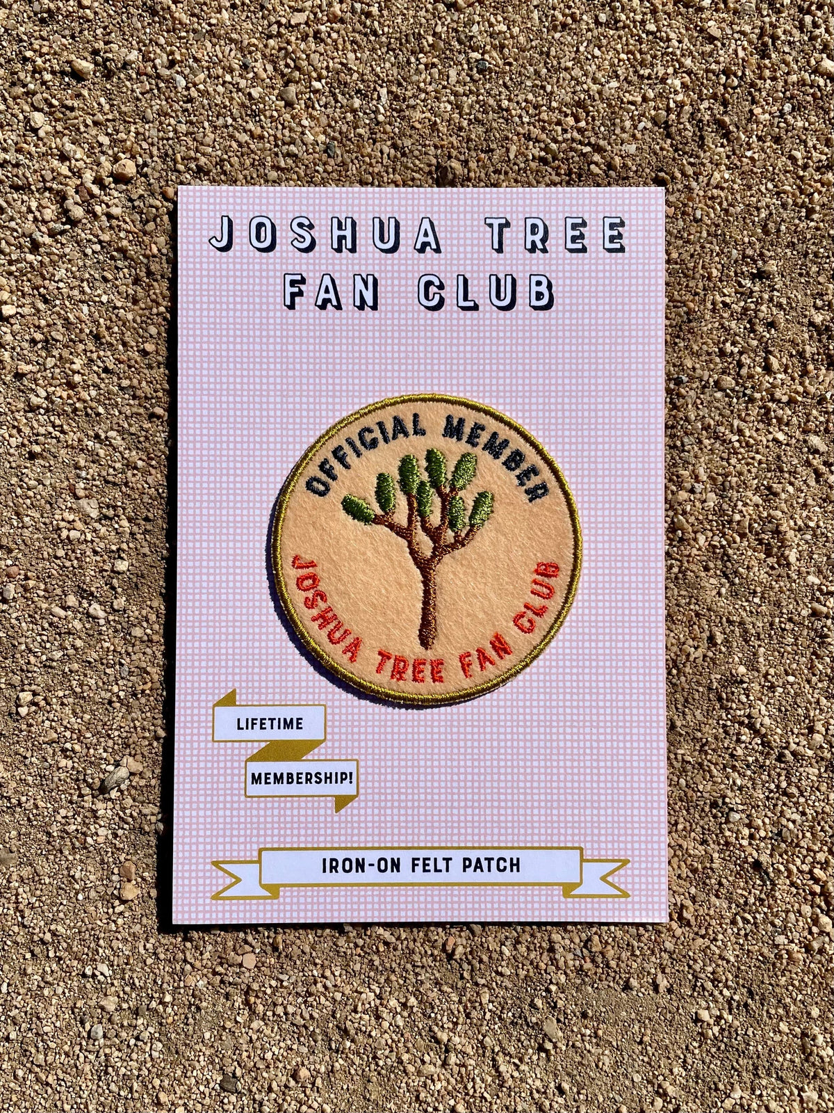 A Joshua Tree Fan Club Patch on a cardboard backing, featuring an embroidered design of a Joshua Tree on a light peach felt base.