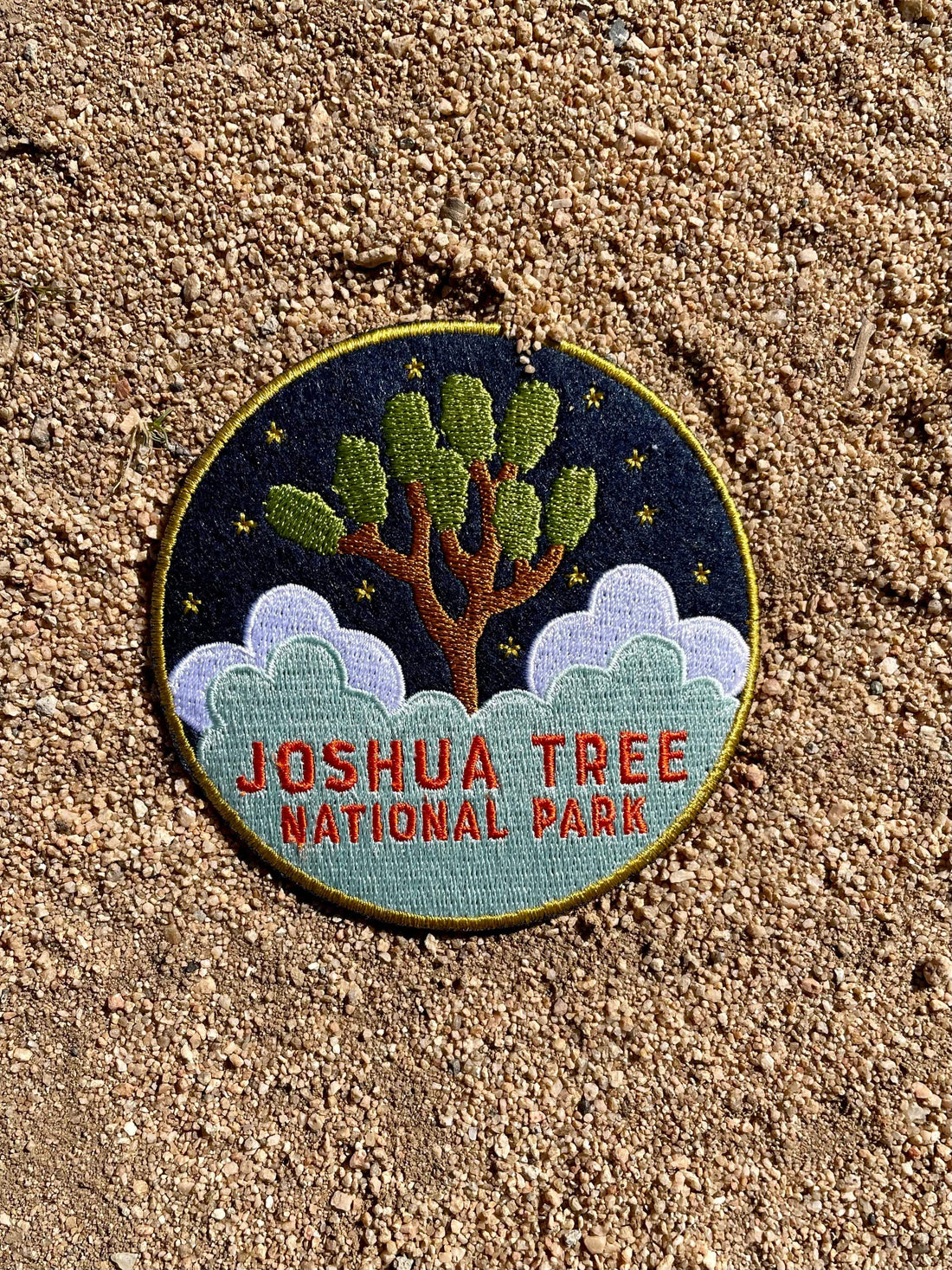 A round navy blue felt patch with embroidered white text and imagery related to Joshua Tree National Park. 