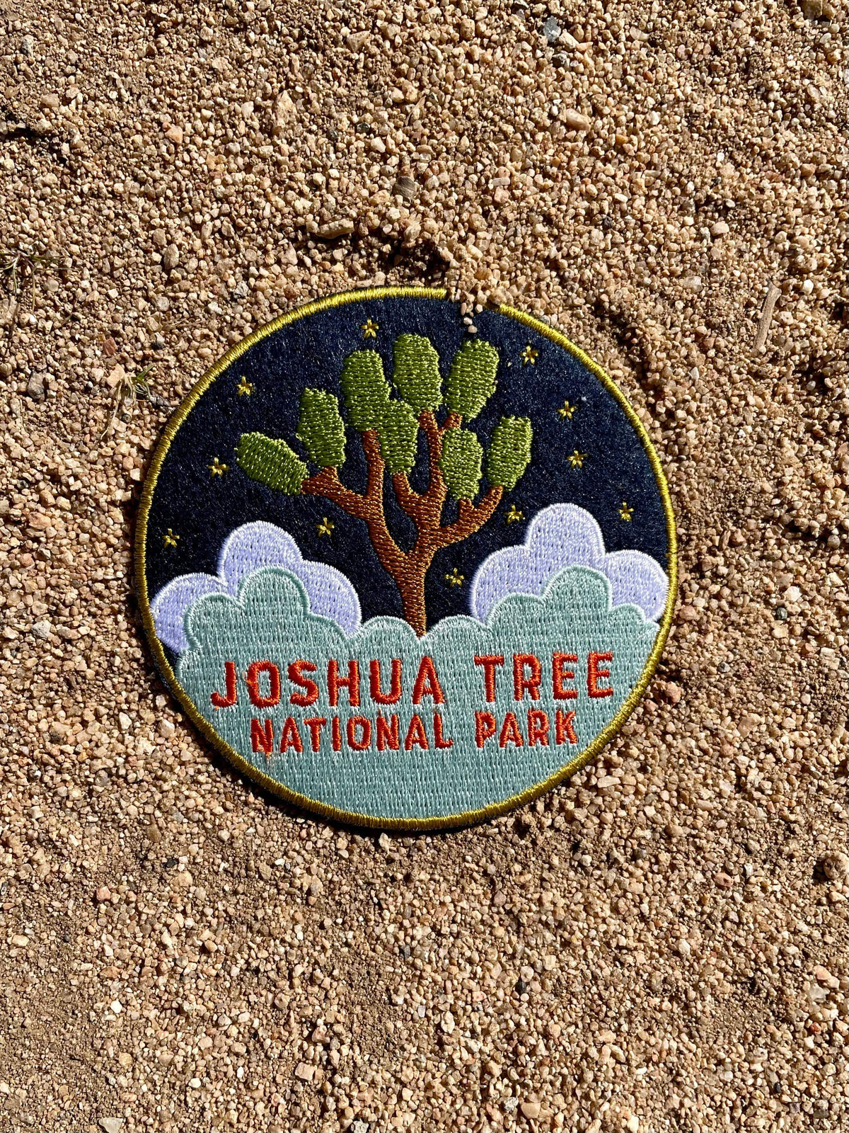 A round navy blue felt patch with embroidered white text and imagery related to Joshua Tree National Park. 