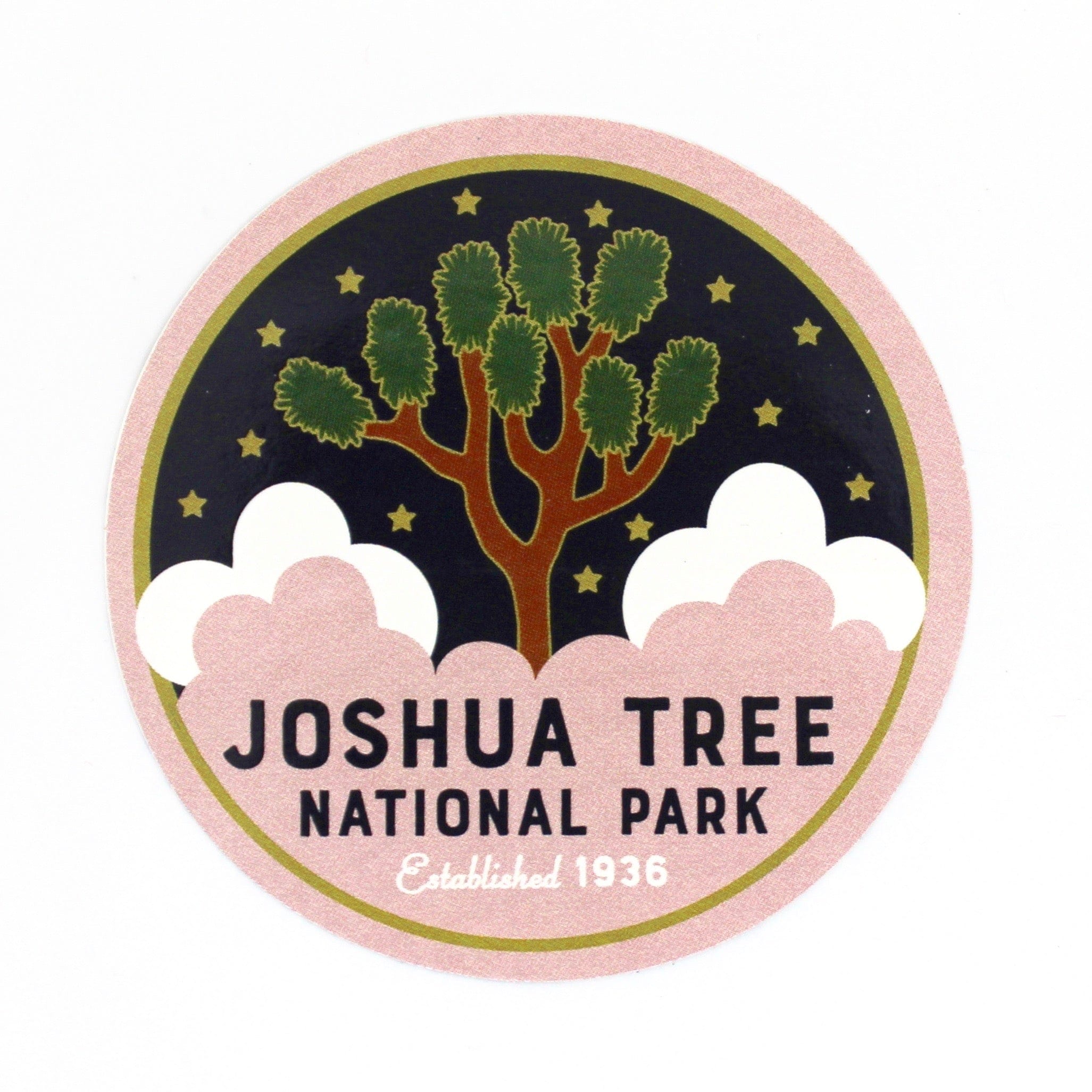 A round sticker with an illustration of Joshua Tree National Park, predominantly featuring a tree with green leaves, against a black background with pink at the bottom.