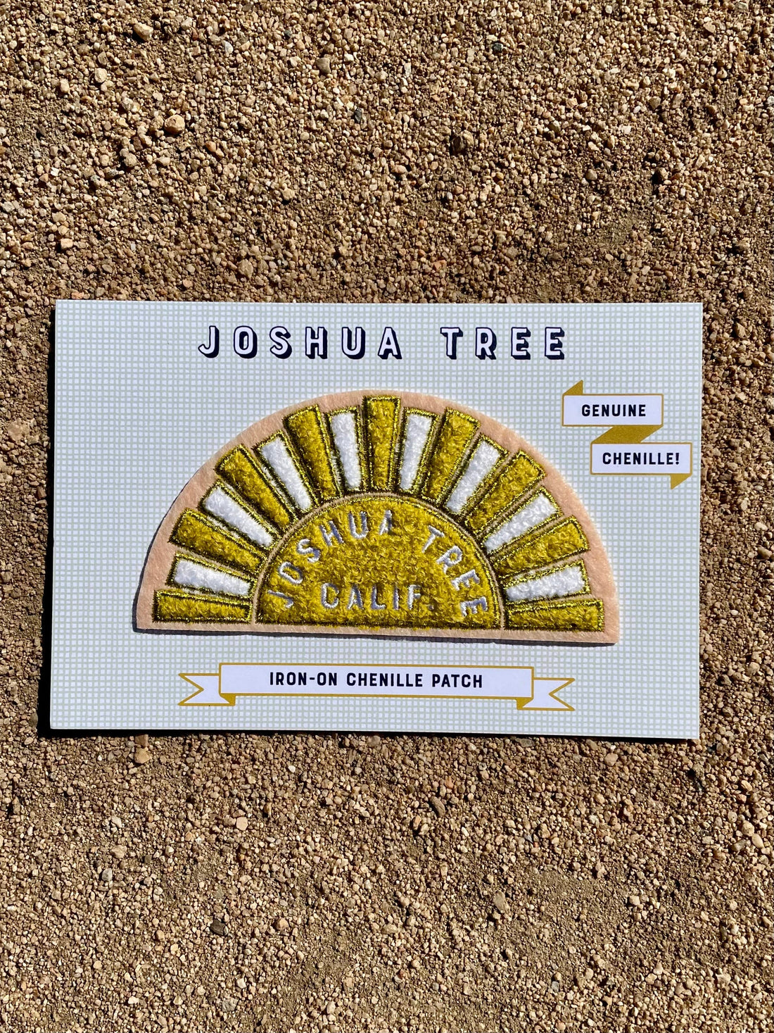 A chenille patch depicting a stylized yellow and white sun with 'Joshua Tree Calif.' text, designed on a pink felt base with gold metallic embroidered details. 